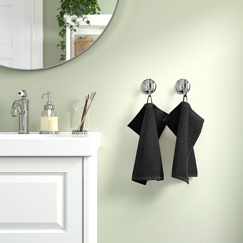 Toalla de algodón beige sobre ganchos cromados en baño.