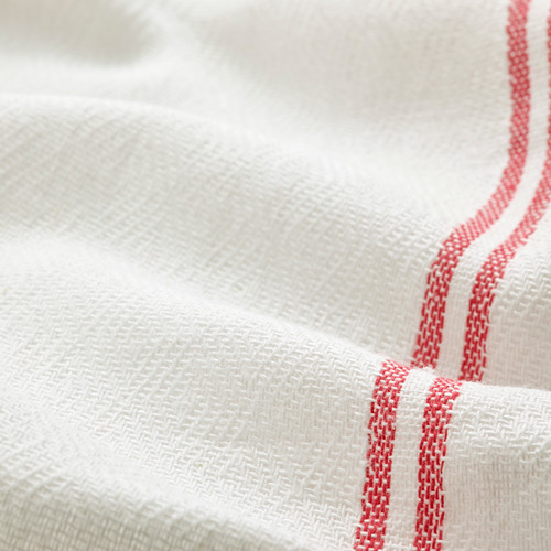 Primer plano de tela blanca cuidadosamente doblada con costuras rojas, que muestra tela de primera calidad y artesanía detallada.