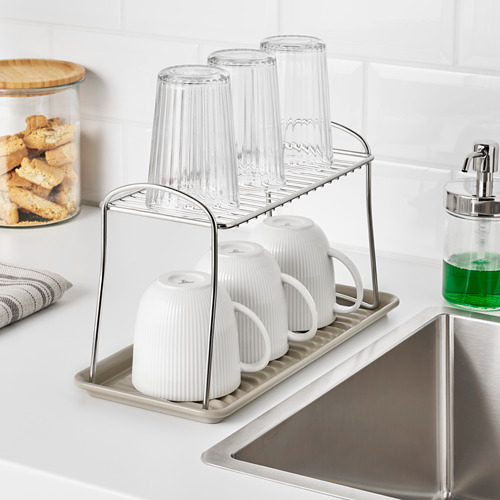 Fregadero de cocina con tazas, vasos y dispensador de jabón.