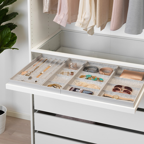 Abra el organizador de joyas en el cajón, colocando collares, anillos y relojes en compartimentos.