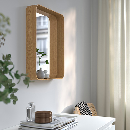 Espejo de madera montado en la pared con estante, jarrón de sujeción, cerca del escritorio con plantas y libros.