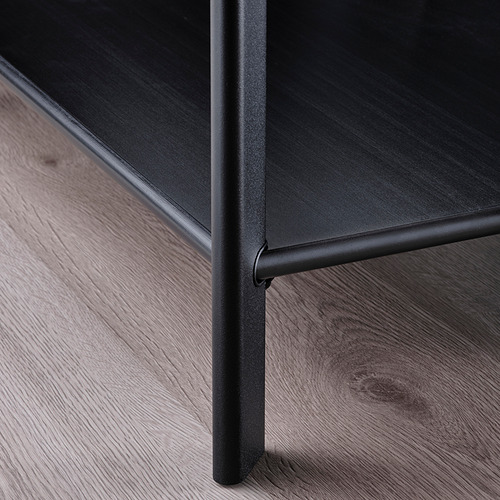 Primer plano de un moderno y elegante borde de mesa de centro negro con patas metálicas.