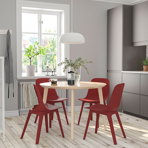 Comedor moderno con mesa redonda LISABO, cuatro sillas rojas, tazas de café negras.