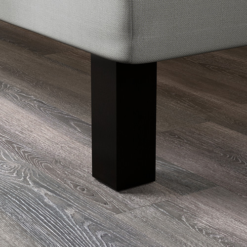 Un primer plano de una robusta pata de cama de madera oscura, que muestra su acabado suave y su sólida construcción.
