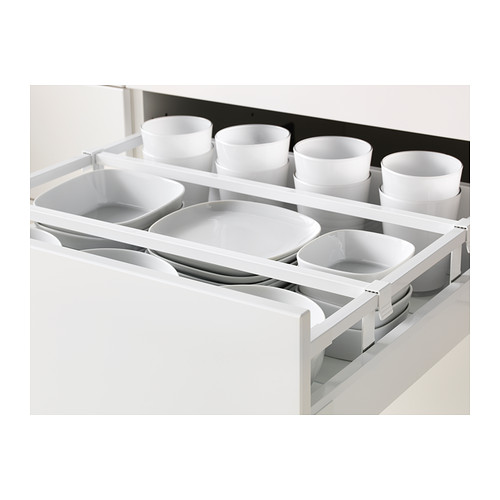 Organizador de cajones de cocina blanco con múltiples compartimentos que contienen tazones y tazas de cerámica blanca. Forma parte del sistema de cocina METOD.