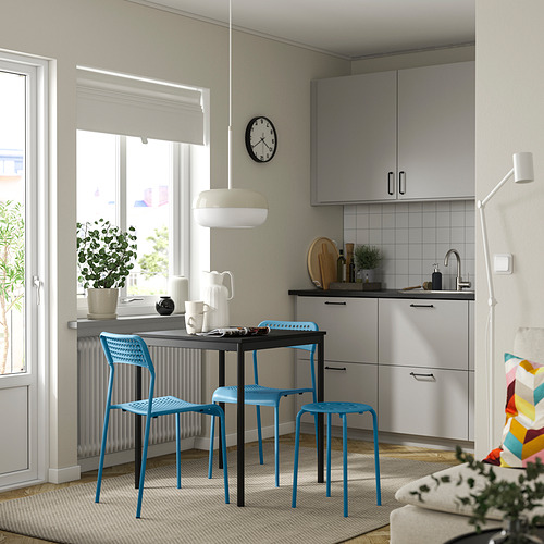 Pequeño juego de comedor moderno con sillas de plástico azul y mesa gris. Diseño limpio y minimalista, ideal para espacios compactos.