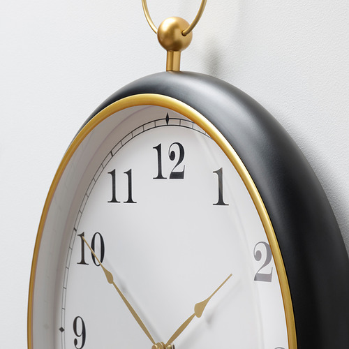 Un reloj de pared grande y elegante con una esfera negra mate y detalles dorados, con números blancos grandes y claros y manecillas doradas.
