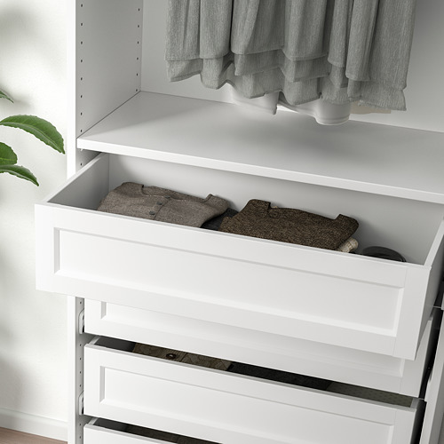 Drawer partially open showing folded clothes in white wardrobe.