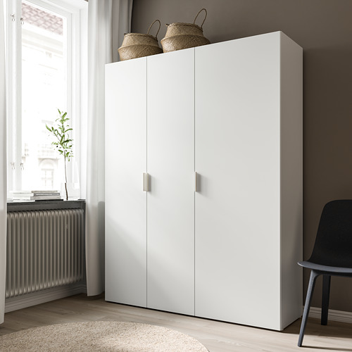 Un armario FONNES blanco alto y elegante con dos puertas se encuentra contra una pared. Tiene cestas tejidas en la parte superior y una estética moderna.