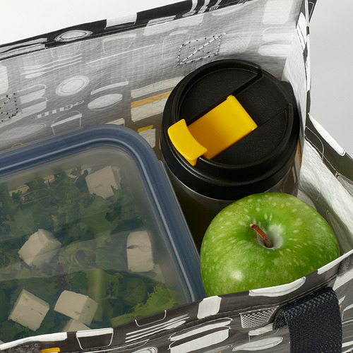 Abra la taza de viaje aislada junto a la manzana verde y el recipiente de ensalada en la bolsa del almuerzo.