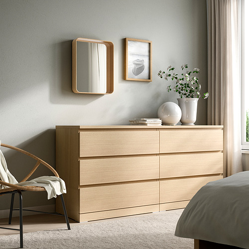 Cómoda de madera con espejo DVÄRGSYREN, cama grande, silla y toalla.