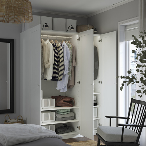 Armario del dormitorio abierto, exhibiendo camisas y ropa doblada en estantes. Iluminación integrada y cajas organizadoras interiores. Mueble blanco con barra para colgar.