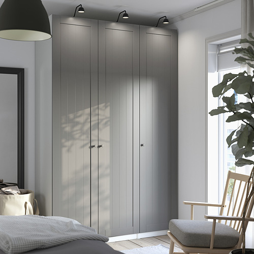 Dormitorio moderno con gran armario PAX gris y acogedora silla junto a una ventana.
