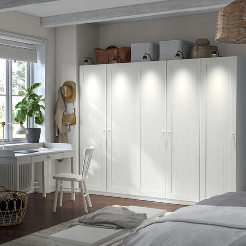 PAX wardrobe stands tall beside desk, centerpiece with storage, bags on top, boxes inside, bright and modern in cozy room.