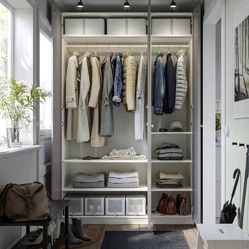 Armario ordenado con perchas y estantes, ropa y accesorios cuidadosamente organizados, que incluyen chaquetas colgantes, suéteres doblados y cajas apiladas.