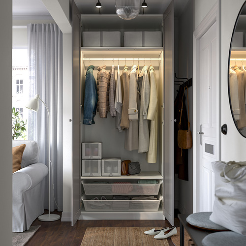 Armario con ropa, estanterías en caja, cesta, lámpara, silla, espejo, puerta con percha.