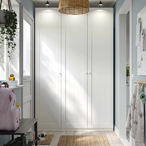 Armario PAX blanco con decoración, líneas limpias, lámpara arriba, tiradores visibles.