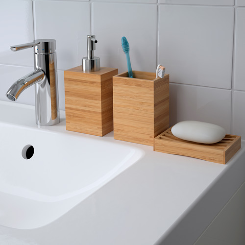 Fregadero blanco con grifo cromado, dispensador de jabón de madera, porta cepillos de dientes con cepillo de dientes azul y jabonera con jabón blanco.