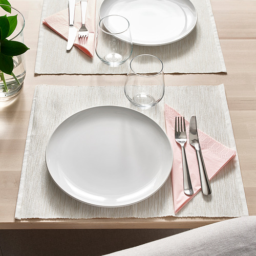 Dos vajillas con platos blancos, cubiertos, vasos y servilletas rosas sobre esteras tejidas.