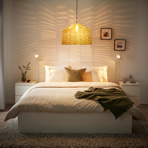 Acogedor dormitorio con cama blanca, manta verde, lámpara KAPPELAND, mesitas de noche y marcos de pared.