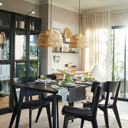 Comedor moderno con mesa negra, luces de mimbre, vitrina y acogedora alfombra.