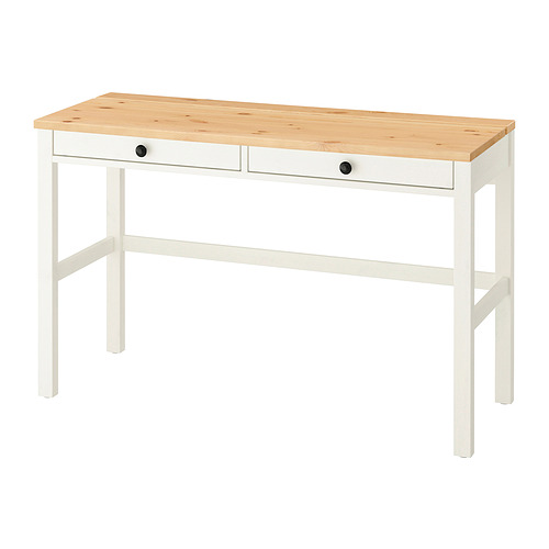 Un escritorio HEMNES blanco y de madera clara con dos cajones y patas robustas.
