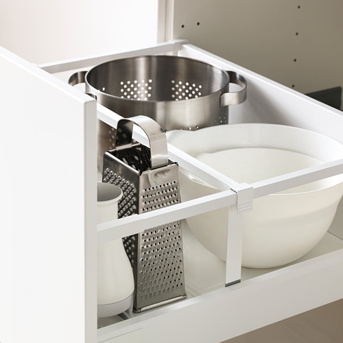 Gabinete de cocina blanco abierto que muestra el colador de peltre y los ralladores almacenados ordenadamente en un estante blanco.