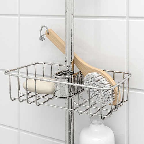 Carrito de ducha metálico con jabón y cepillo apoyado contra la pared de azulejos blancos.
