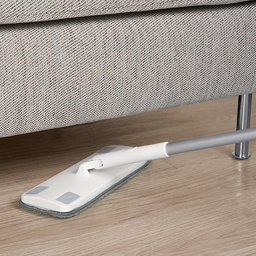 La mopa blanca con almohadilla de microfibra gris se apoya en los modernos muebles tapizados en gris sobre suelo de madera.
