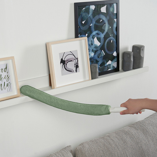 Mano con mango de limpieza PEPPRIG y almohadilla de microfibra para fregar pared blanca. Incluye mango ajustable y múltiples cabezales de limpieza.