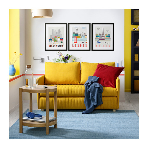 Luminoso salón con sofá cama amarillo, almohadas rojas y azules, estampados urbanos y mesita auxiliar de madera.