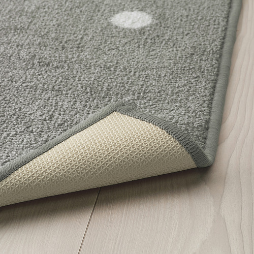 Una alfombra gris con puntos blancos sobre un suelo de madera, con un respaldo de goma texturizada para un agarre antideslizante.