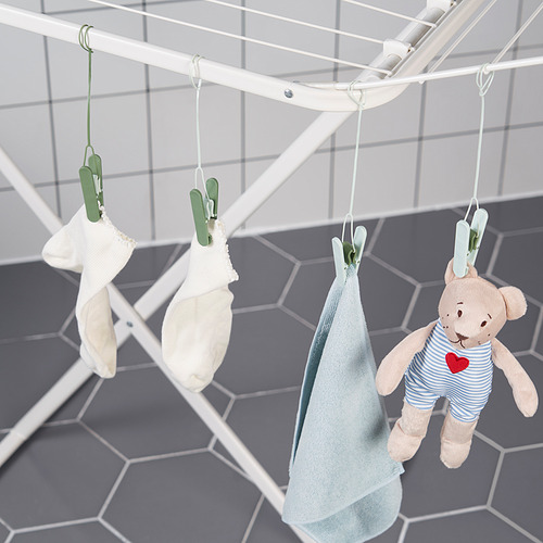 Las pinzas para la ropa cuelgan la ropa en un tendedero, incluidos artículos para bebés y un osito de peluche.
