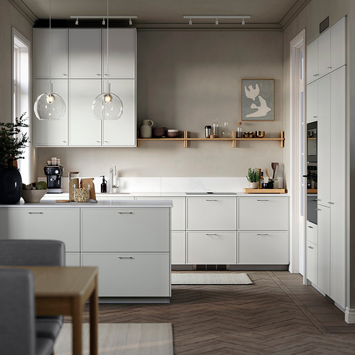 Cocina moderna con gabinetes blancos, piso de madera, luces colgantes y un comedor.