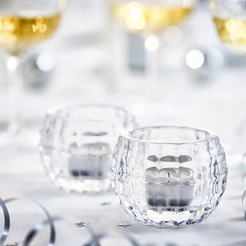 Candelabros de vidrio transparente sobre una mesa. Una luz suave y encendida. Diseño elegante, parte de la colección FRÖJDA.