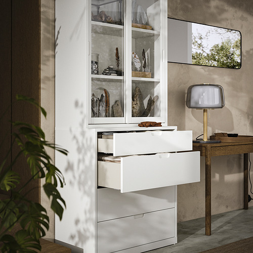 Habitación moderna con armario y cofre TONSTAD blanco, puertas de cristal, escritorio de madera, lámpara y planta.