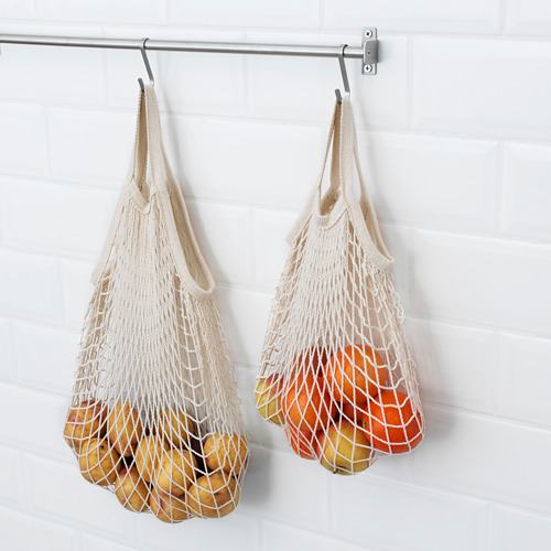 Dos bolsas de malla cuelgan de ganchos, llenas de productos, almacenando y manteniendo las frutas frescas.