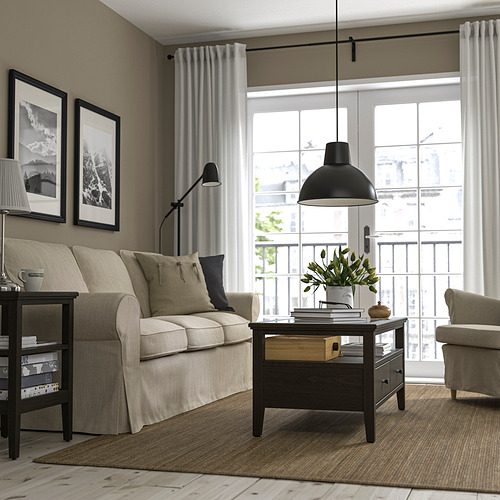 Sala de estar moderna con mesa de centro IDANÄS, muebles beige, lámpara colgante negra, grandes ventanales y fotos de pared.