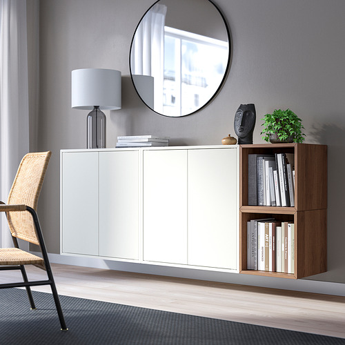 Habitación moderna con armarios EKET, libros, lámpara, escultura, silla de mimbre y un gran espejo.