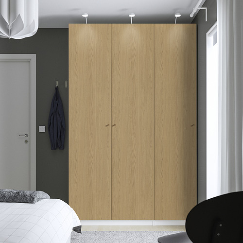 Dormitorio moderno con gran armario de madera PAX, cama blanca y prenda azul.