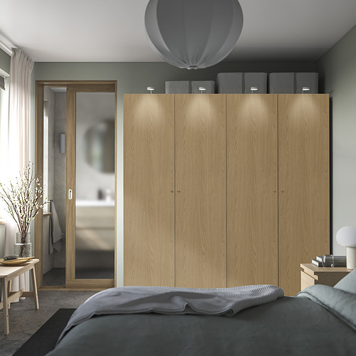 Dormitorio moderno con gran armario de madera PAX, decoración gris, puertas de cierre suave, encimera iluminada y ambiente relajante.