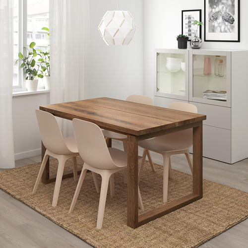 Moderno comedor con mesa y sillas MÖRBYLÅNGA. Acabado en roble natural, sillas beige claro, alfombra, ventana, armario, planta.