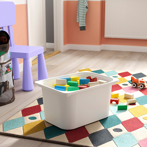 Contenedor de almacenamiento blanco, lleno de bloques de colores, sobre alfombra multicolor. Perfecto para que los niños se organicen y jueguen con juguetes.