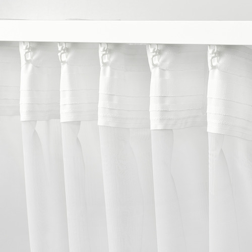 Las cortinas blancas con un sutil patrón en relieve cuelgan cuidadosamente con ganchos, filtrando la luz y ofreciendo privacidad.