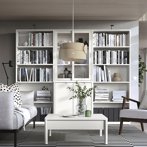 Moderna sala de estar con estanterías y sofás TONSTAD de color blanco roto, con un diseño elegante con puertas de vidrio y detalles en madera.