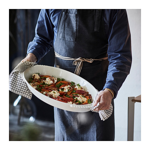Person holding a large oven dish with roasted vegetables, ready to serve.