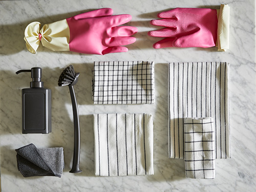 Guantes rosas, corbata amarilla, dispensador de jabón negro, cepillo, toallas, esponjas grises.