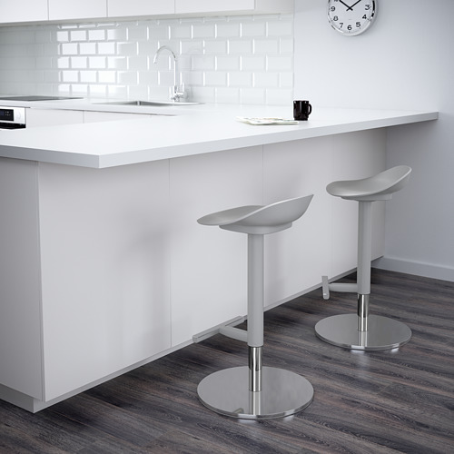 Cocina moderna con encimeras blancas y dos taburetes de bar ajustables con bases redondas.