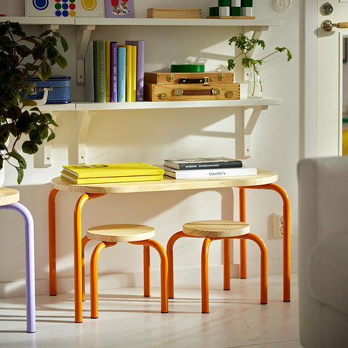 Pequeño conjunto de muebles GREJSIMOJS naranjas con asientos de madera y patas de acero, colocados debajo de un estante blanco con artículos coloridos.