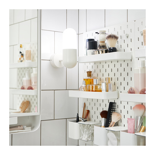 Moderno baño blanco con estantes de tablero perforado y artículos de tocador. Dos luces de cápsula.